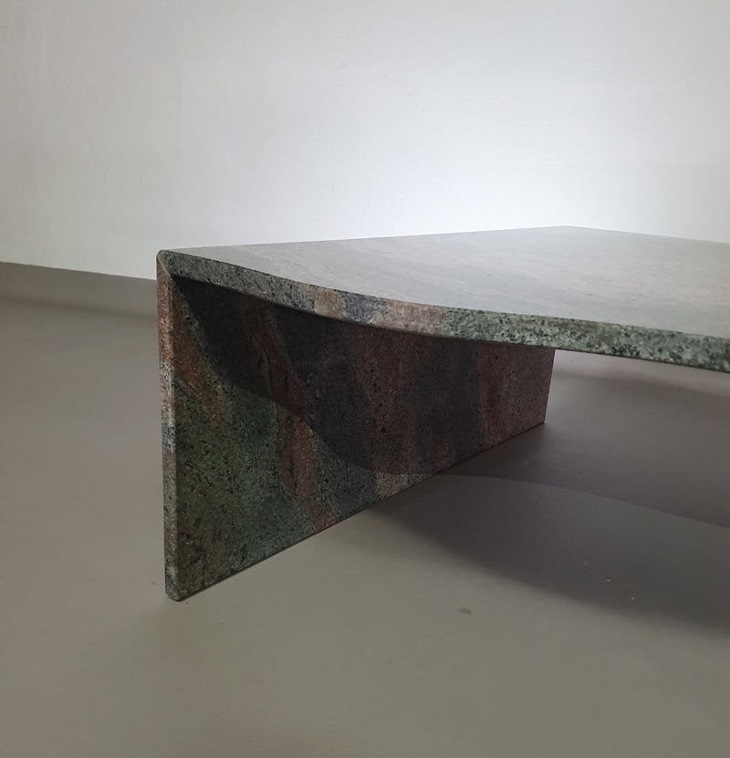 Een grote granieten salontafel met een vrije vorm, drie rechte lijnen die contrasteren met een golvend front. Jaren 70